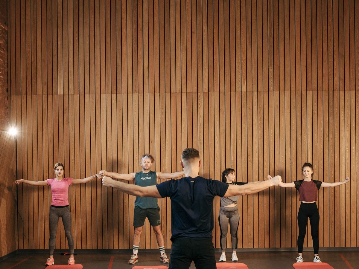 A group class working through a dumbbell set together in a bright studio.